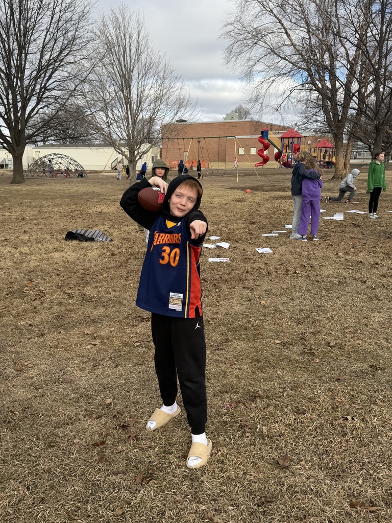 Boy standing outside on a playground holding a football