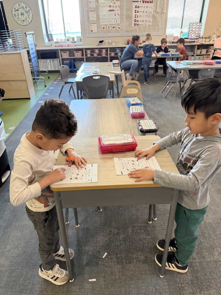students standing at a desk reading to one another