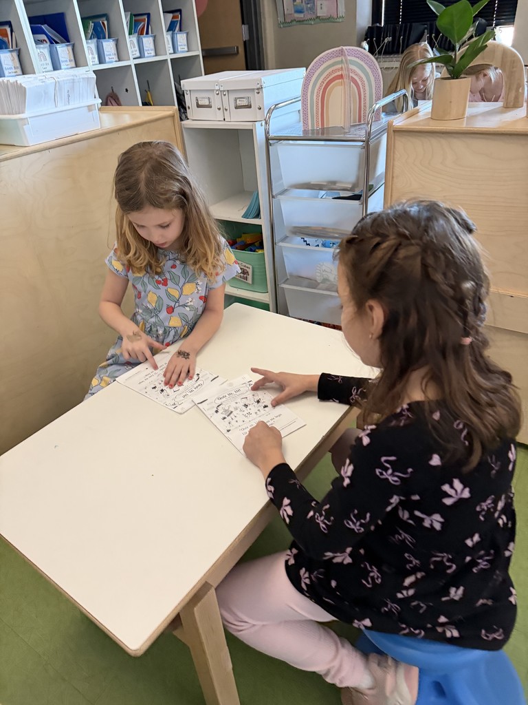 students sitting at a table reading to each other