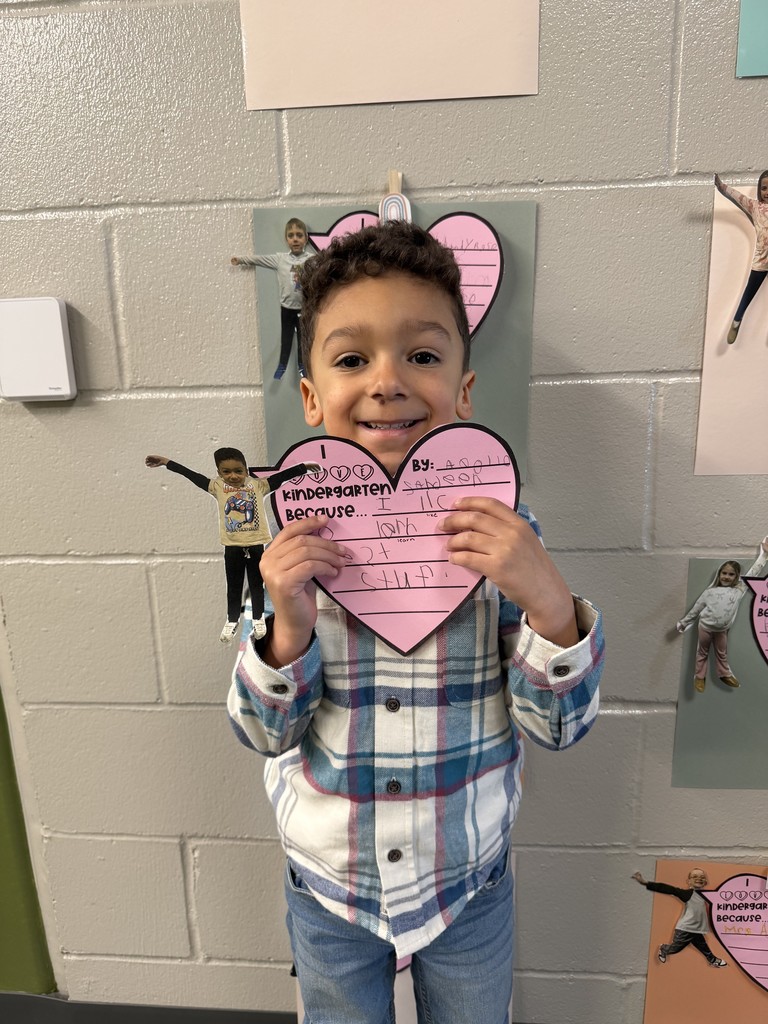 Student holding a writing assignment of why they love kindergarten