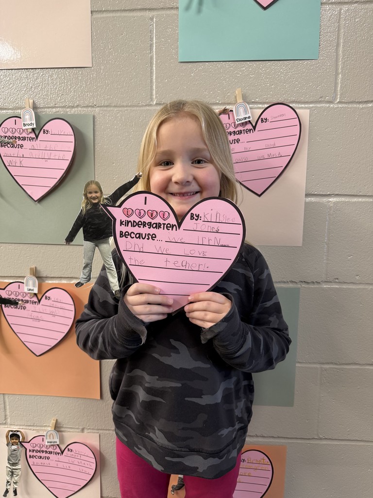 Student holding a writing assignment of why they love kindergarten