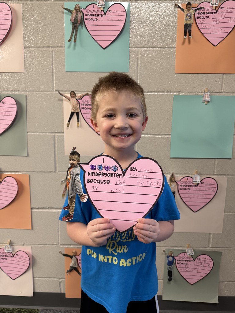 Student holding a writing assignment of why they love kindergarten