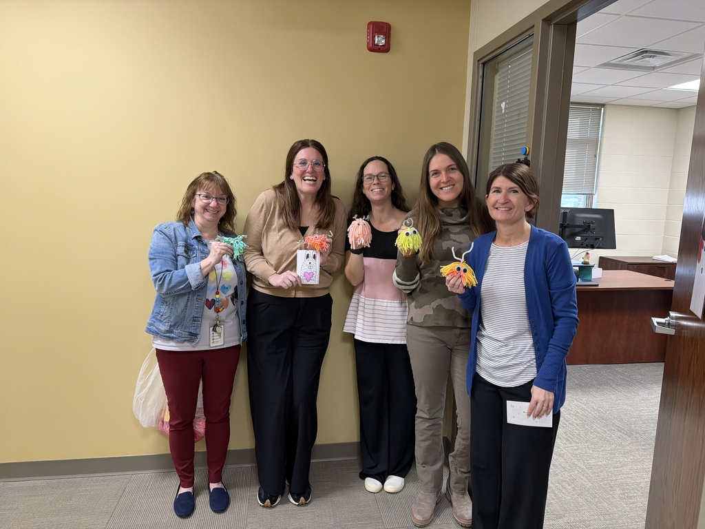 five District office staff members each holding their yarn monsters from gretna elementary school.