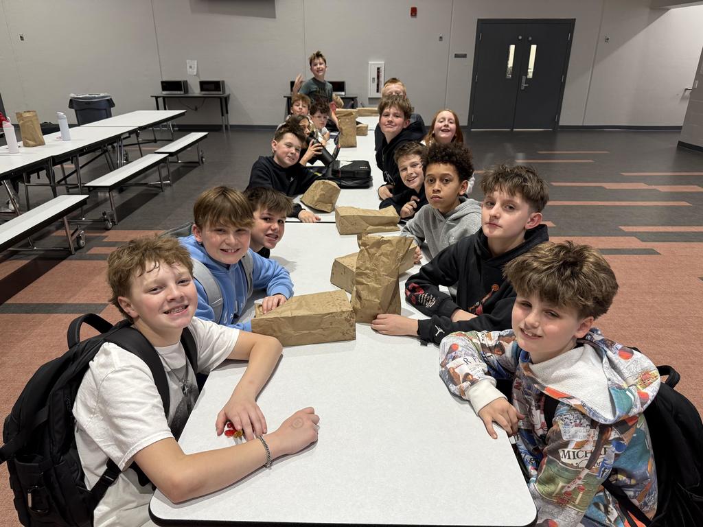 Students smiling at a lunch table. 