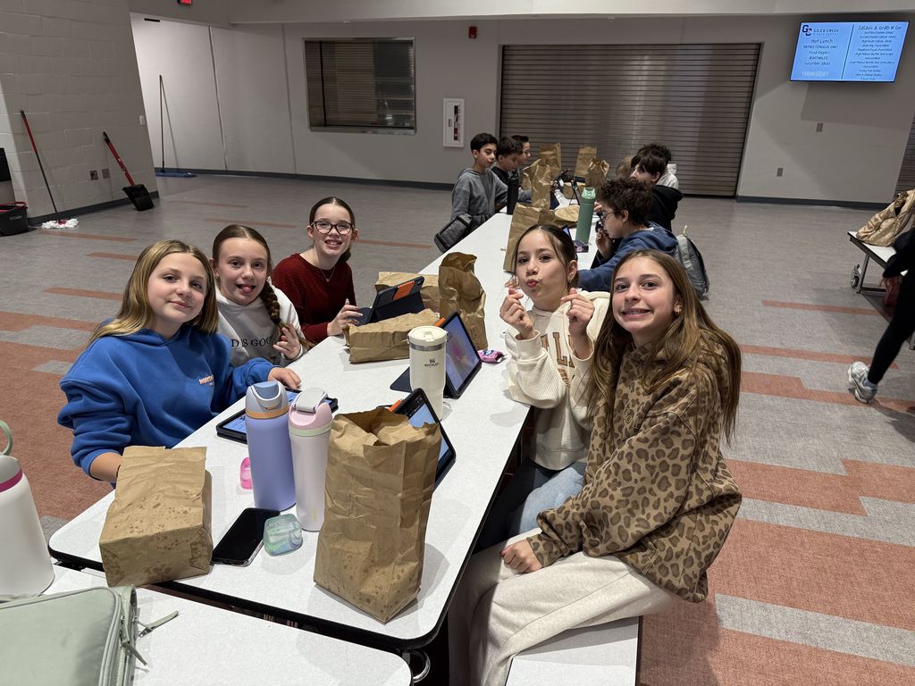 Students smiling at a lunch table. 