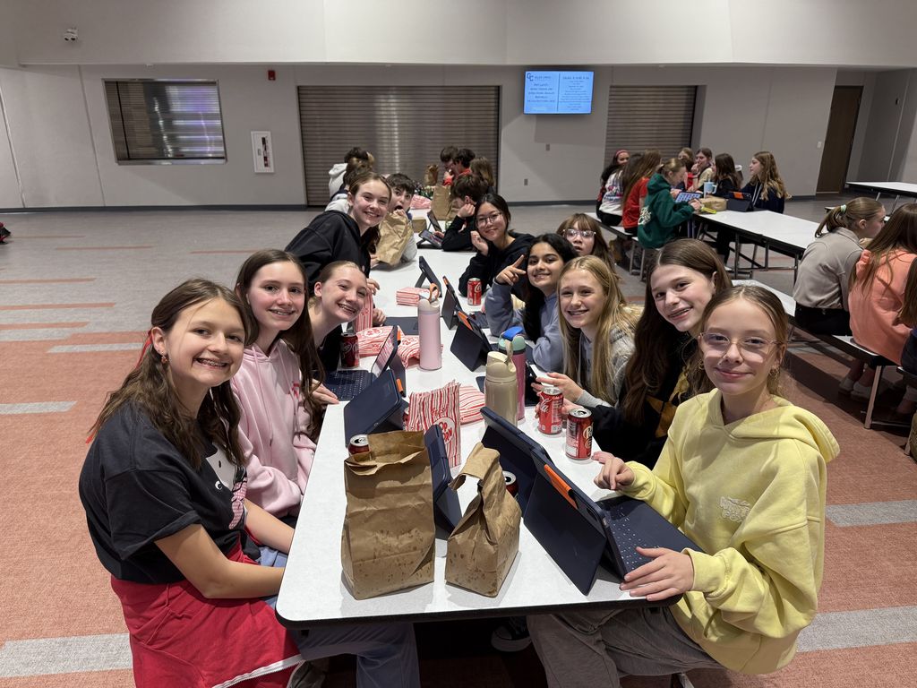 Students smiling at a lunch table. 