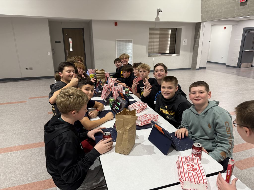 Students smiling at a lunch table. 