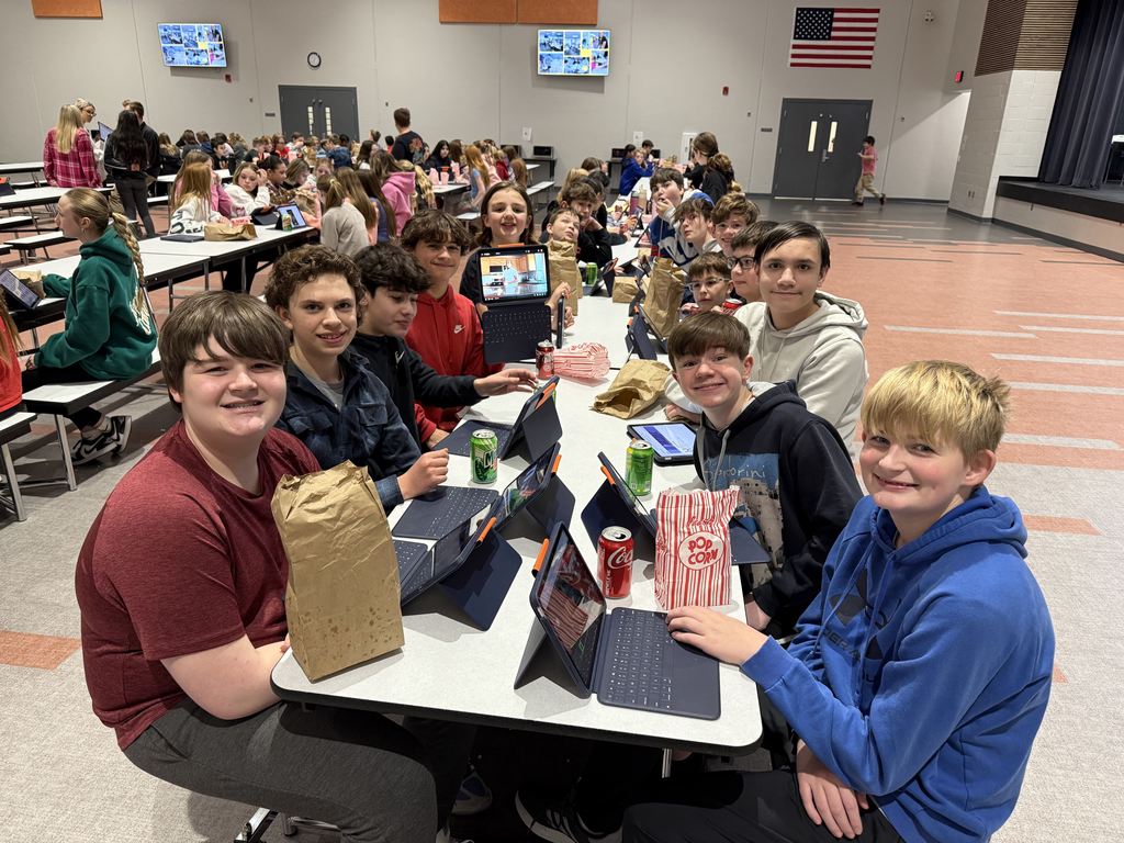 Students smiling at a lunch table. 