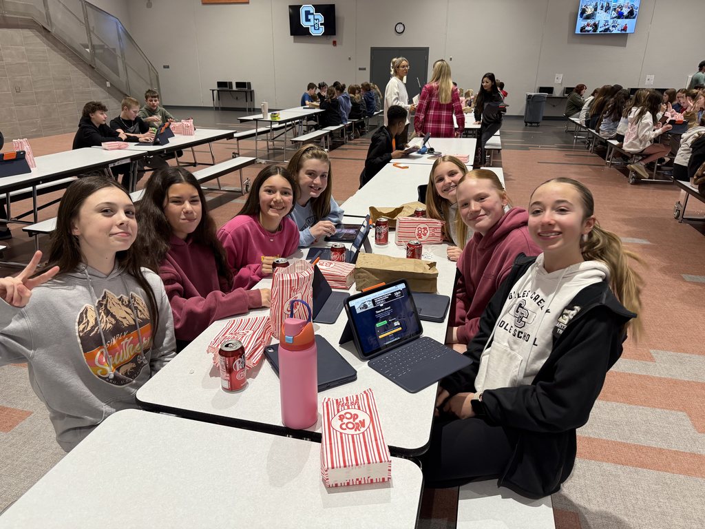 Students smiling at a lunch table. 