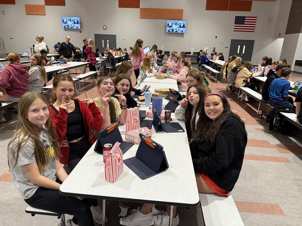 Students smiling at a lunch table. 