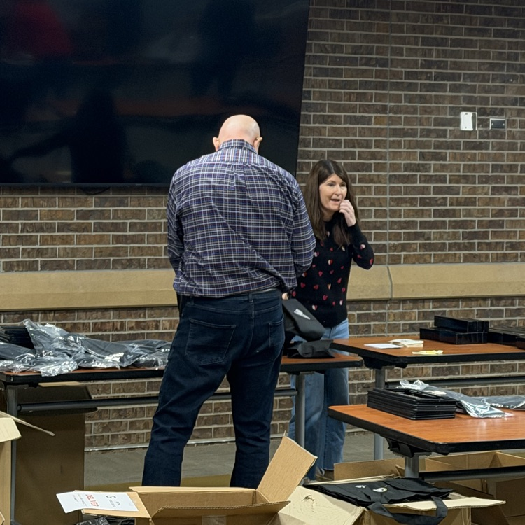 several workers at tables filling gift bags surrounded by boxes