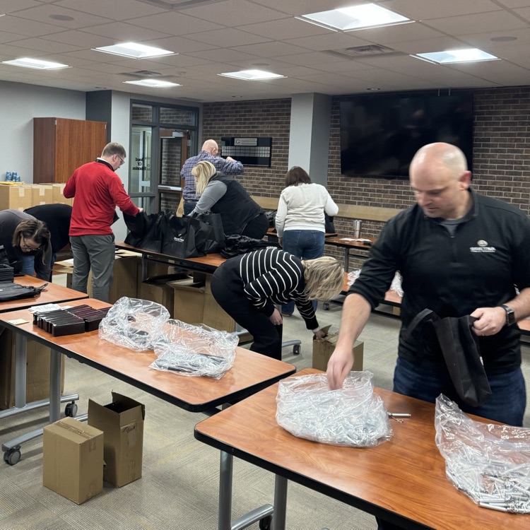 tables lined up with items to be put into gift bags with workers from district office sorting