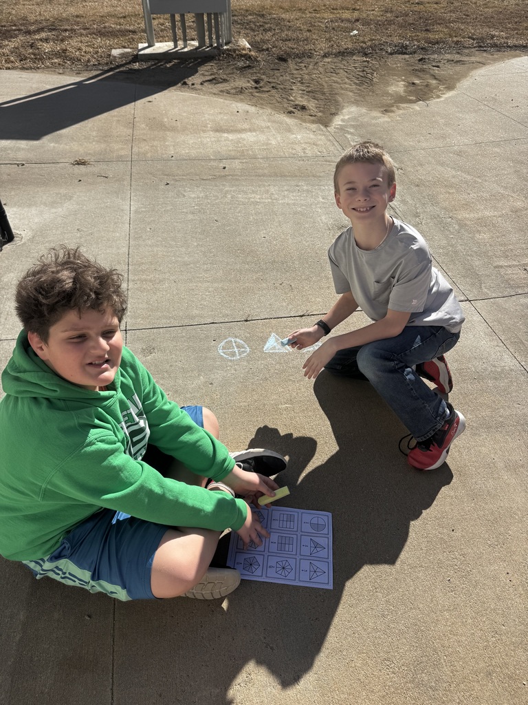 Two boys on the ground smiling while chalk drawings show on the cement.