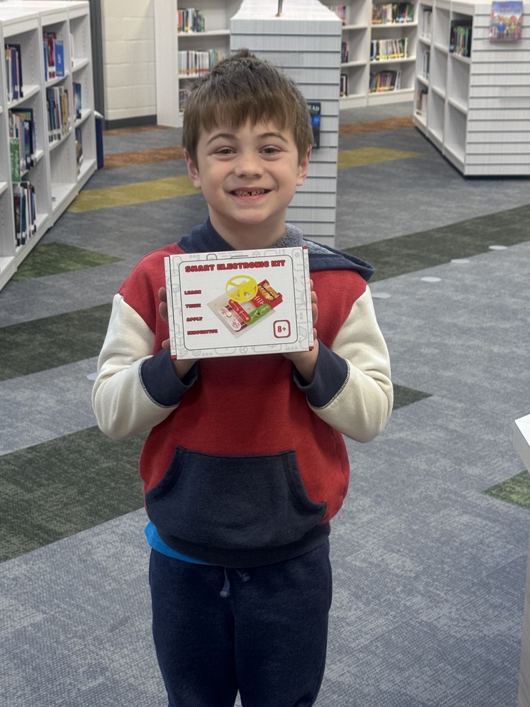 student holding up a poster smiling