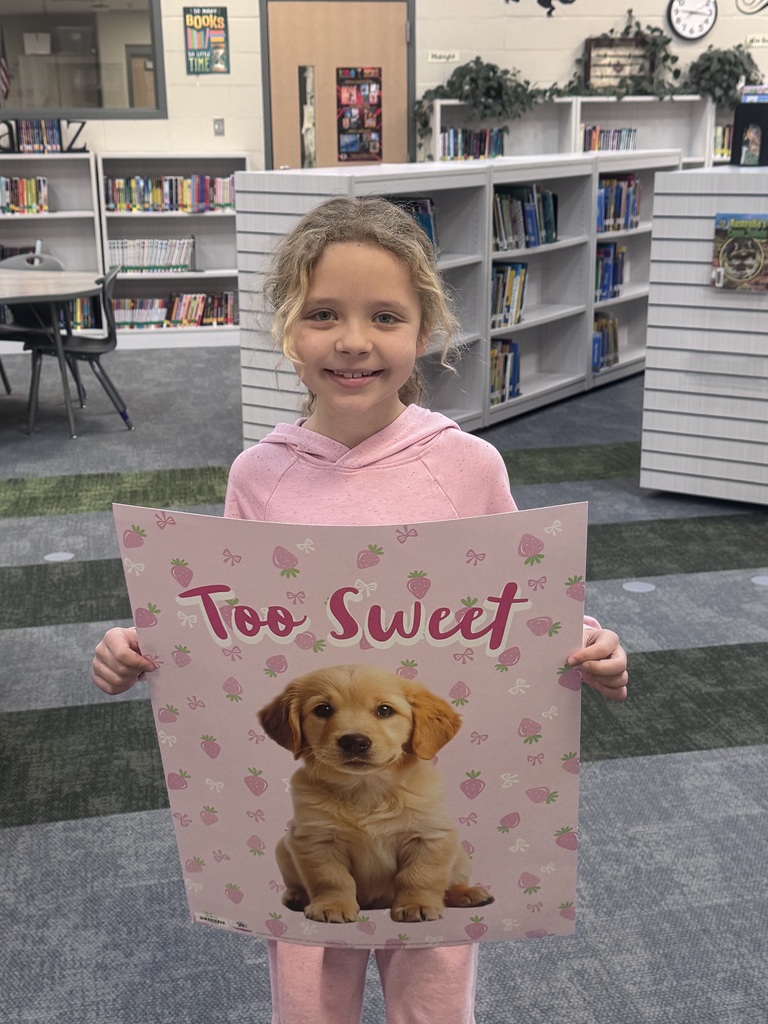 student holding up a poster smiling