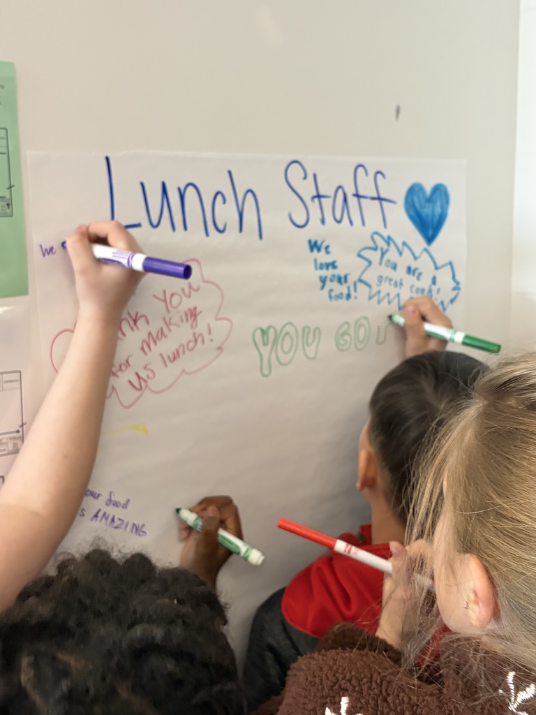 Students write on a poster encouraging words for our lunch staff.