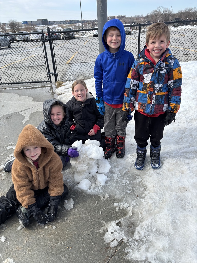 5 first graders are building a structure out of snow balls.