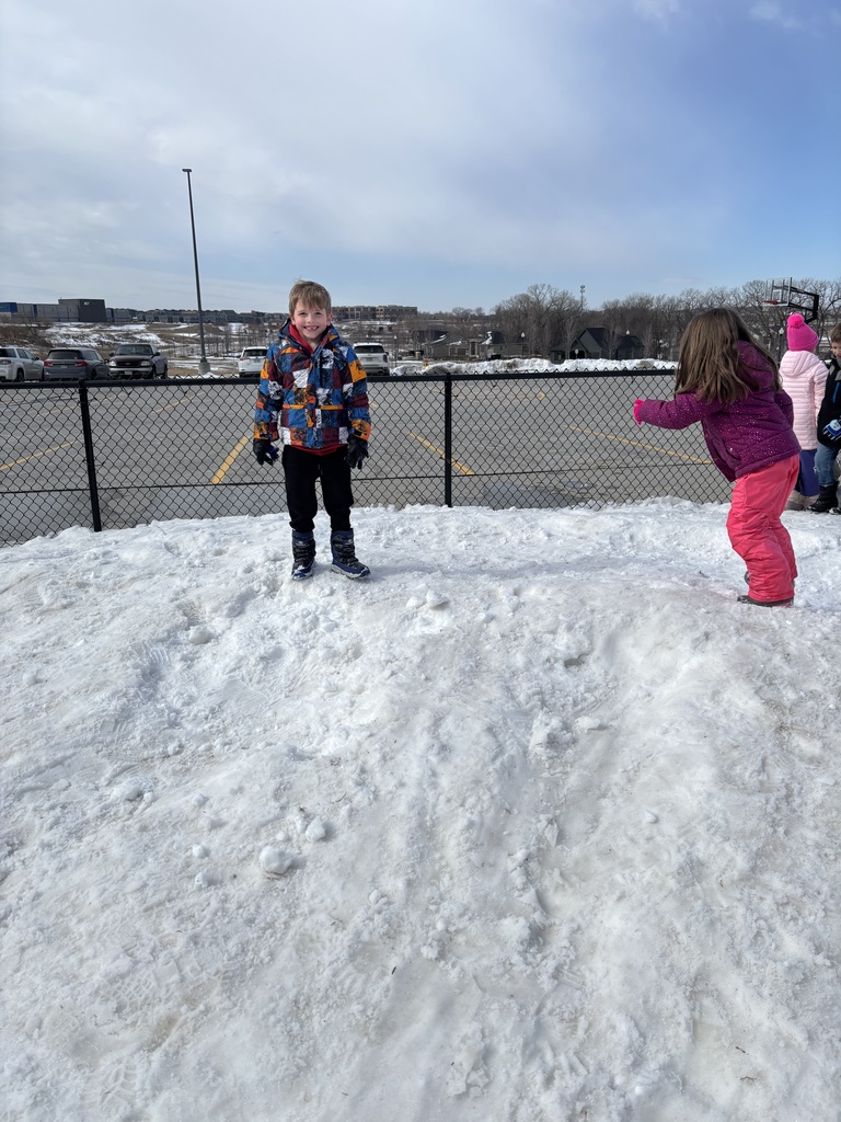 A first grade students smiles at a snowy recess.