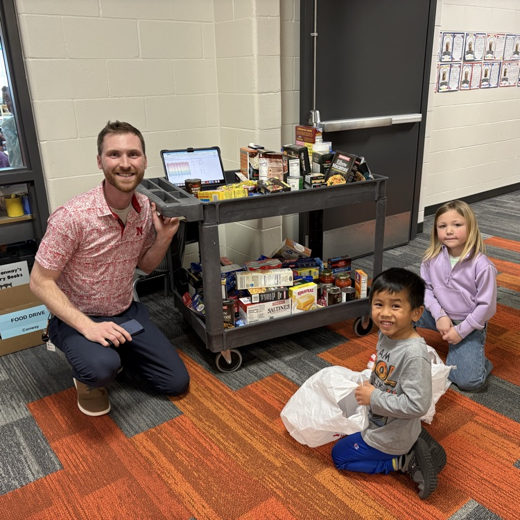 Mr. Dinslage kneels by a car with two first graders collecting food  