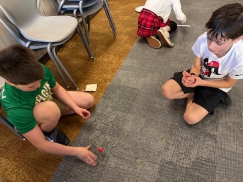 students playing jacks and marbles in a classroom
