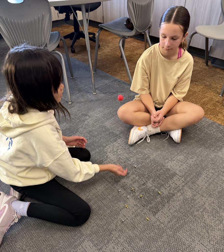 students playing jack and marbles in a classroom