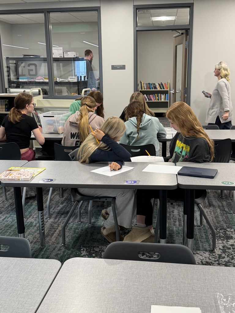 Students are working on drawing and perler beads at tables. 