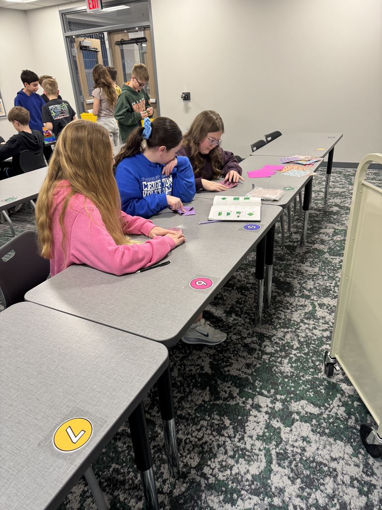 Students are working with origami paper at a table. 