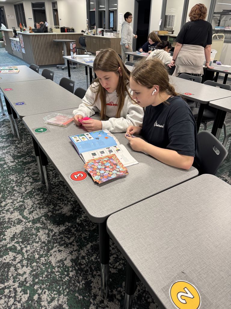 Two girls are working with origami paper. 
