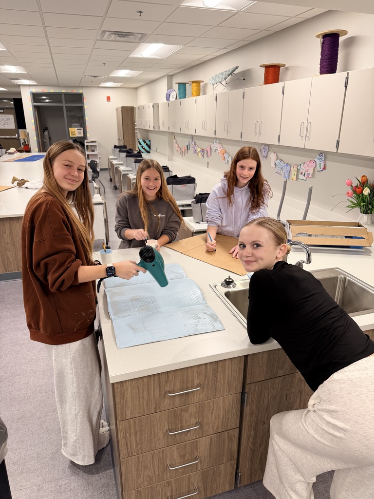 4 girls are working on painting cardboard. 