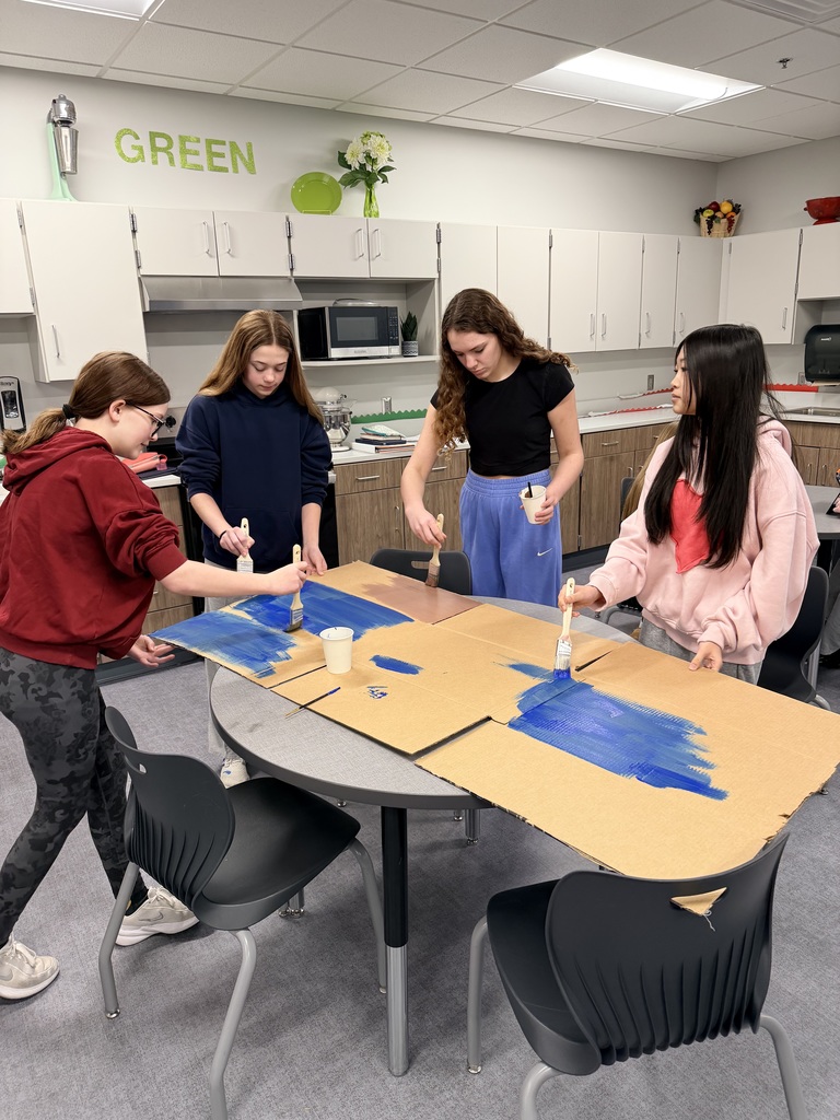 4 girls are working on painting cardboard. 
