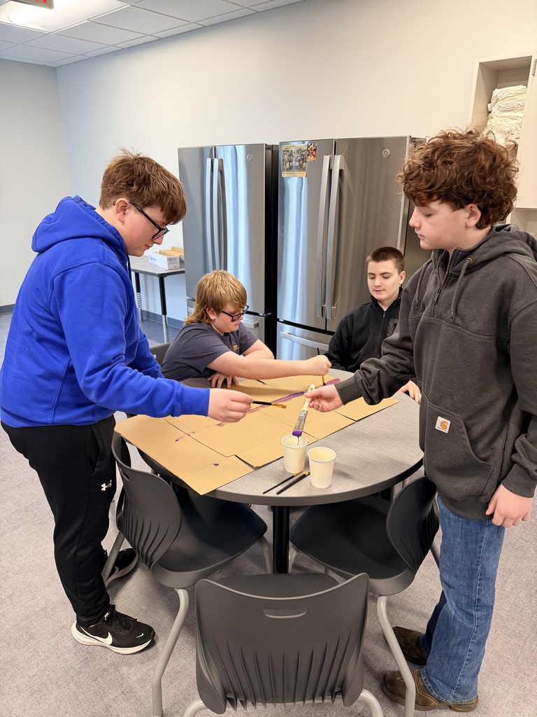 4 boys are painting cardboard. 