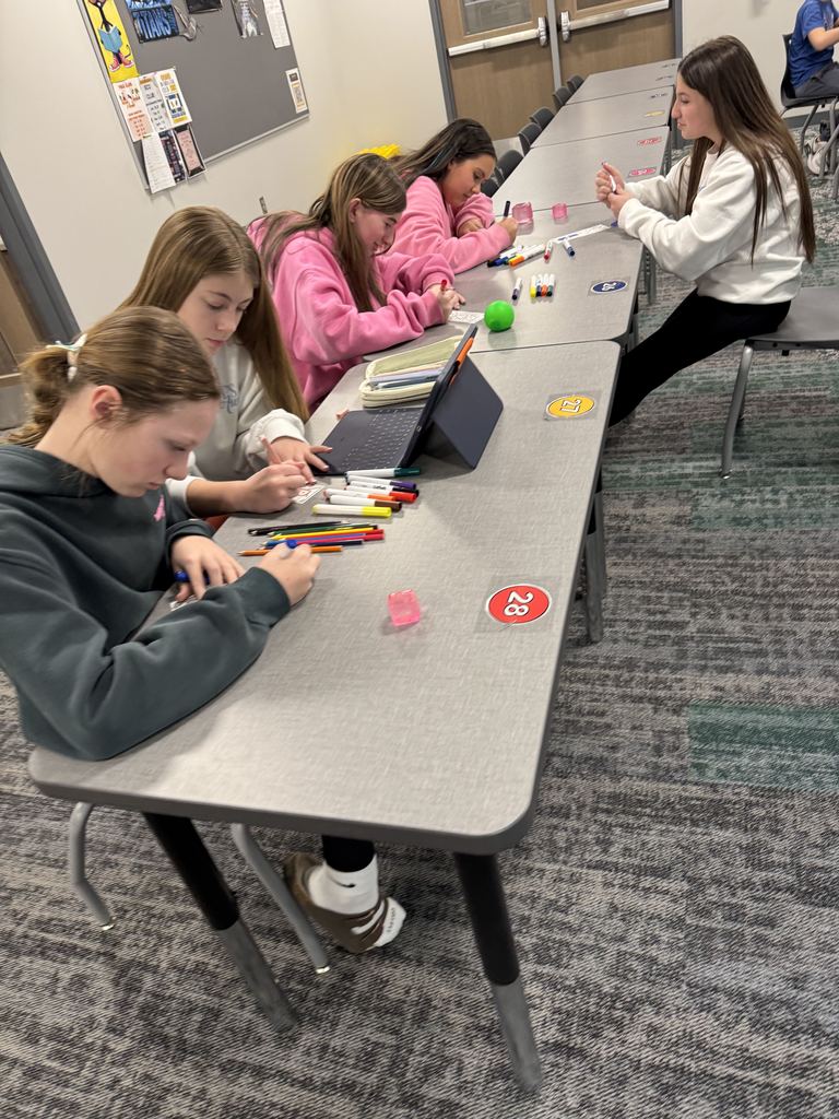 Girls are sitting at a table coloring. 