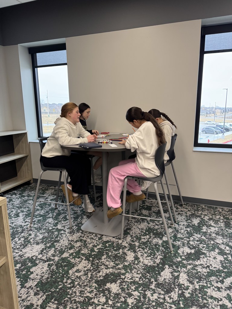 Four girls are sitting at a table coloring. 