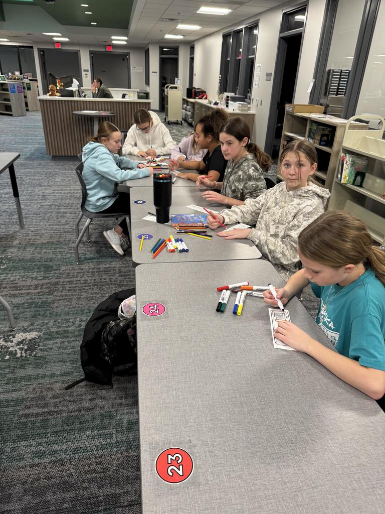 Students are coloring at a desk. 