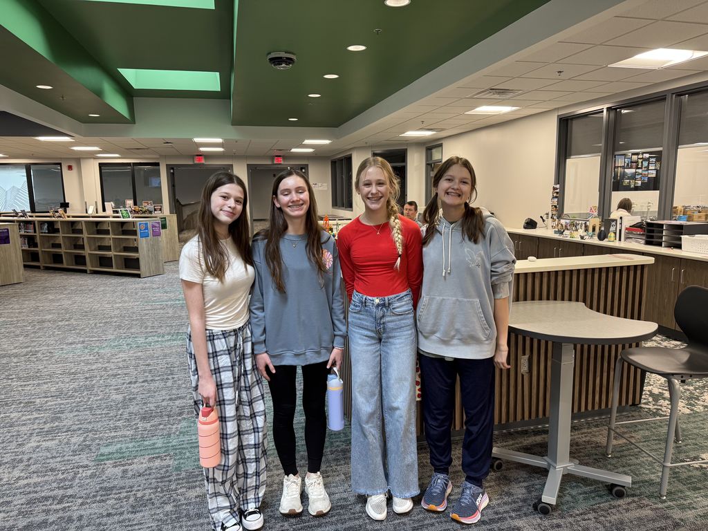 Four girls are smiling at the camera. 