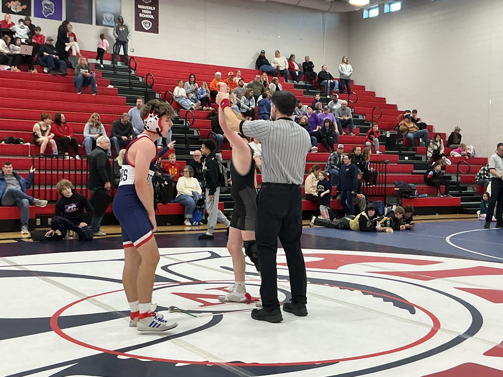 One kid has his hand raised for winning a wrestling match. 