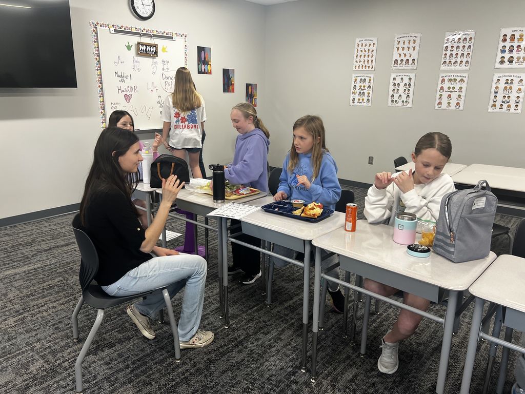 Students are sitting at desks practicing signing with their instructor. 