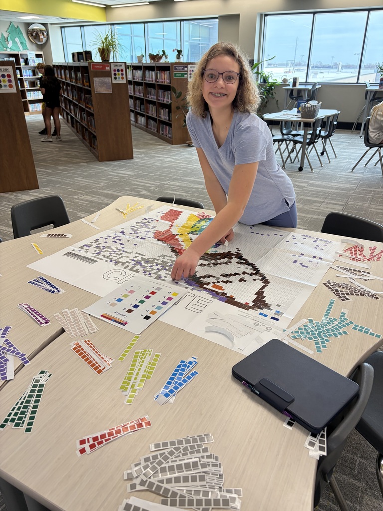 Photo of a female student adding stickers to a sticker mosaic picture.