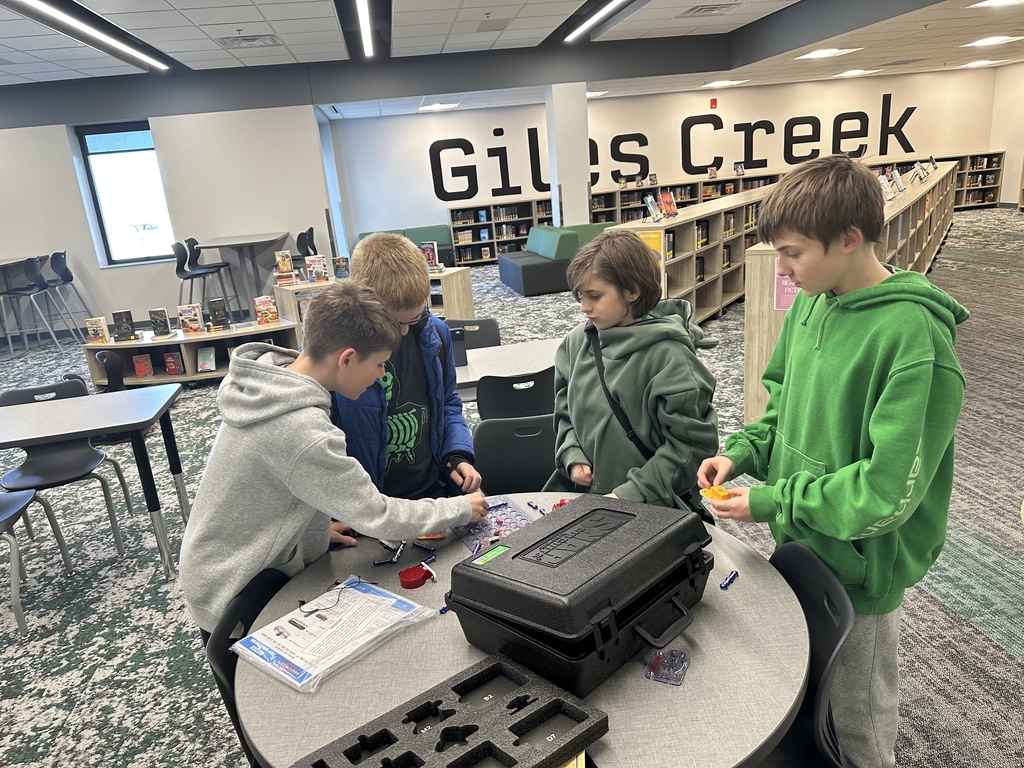 Four boys are around a circle table building with snap circuits. 