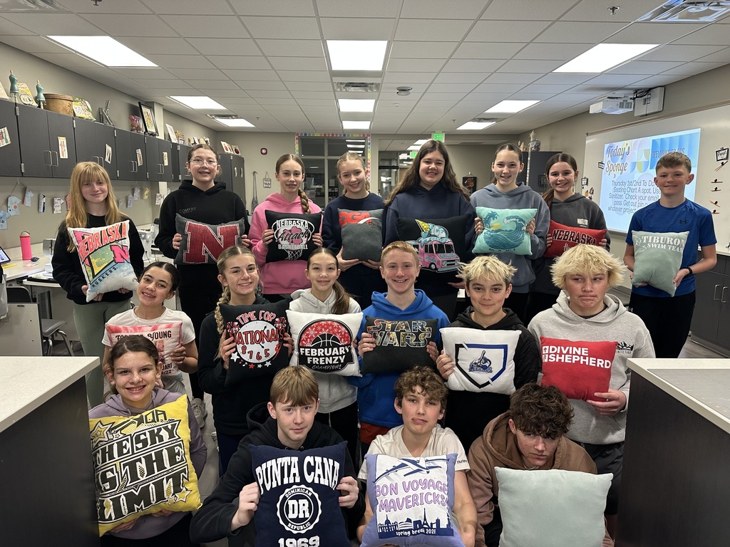 Photo of rows of 7th grade students posing holding their tshirt pillows.