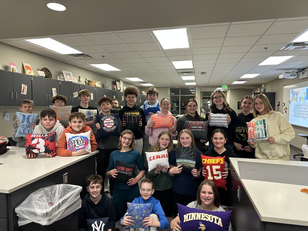 Photo of rows of 7th grade students posing holding their tshirt pillows.