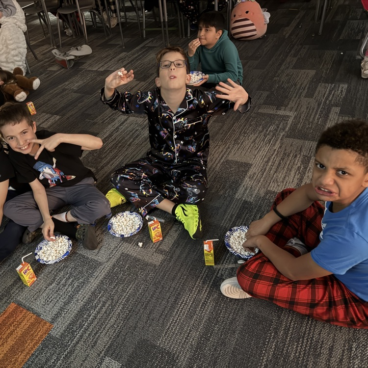 three students are sitting on the floor eating popcorn and making silly faces 