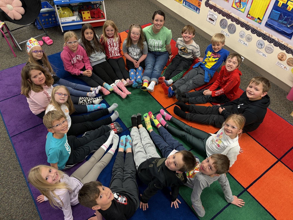First grade students sitting in a circle and showing their colorful socks.
