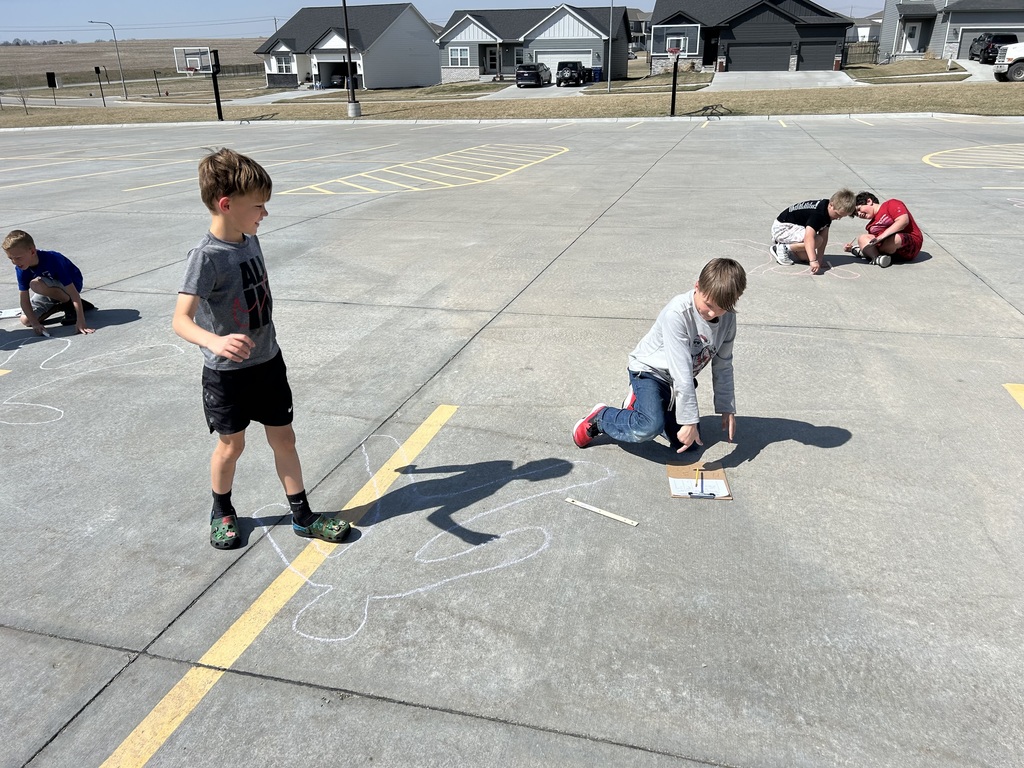students measuring and outlining one another with chalk