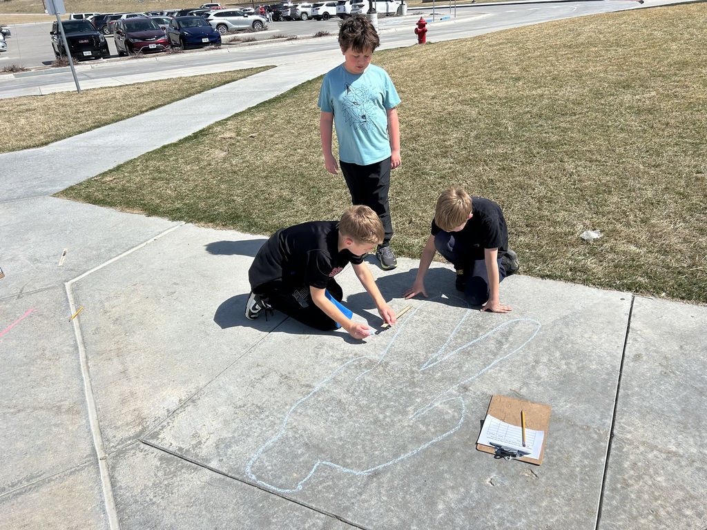 students measuring and outlining one another with chalk