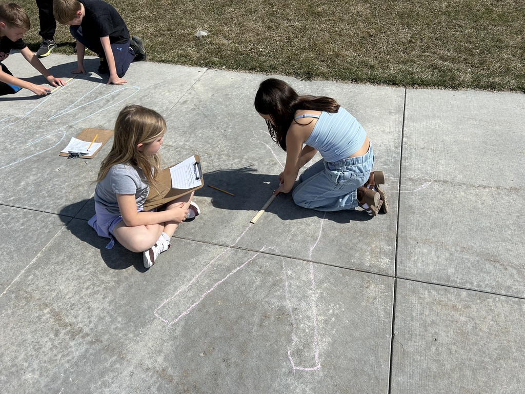 students measuring and outlining one another with chalk