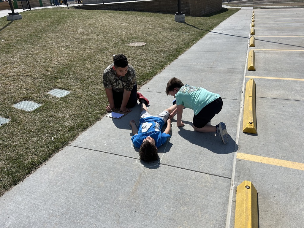 students measuring and outlining one another with chalk