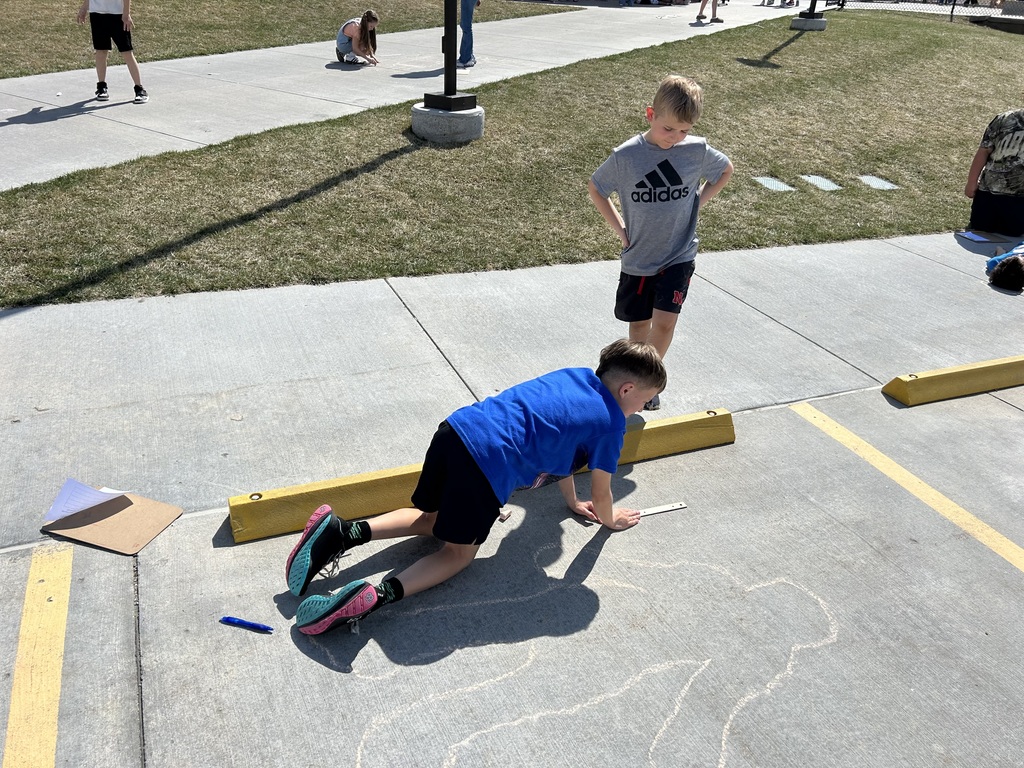students measuring and outlining one another with chalk