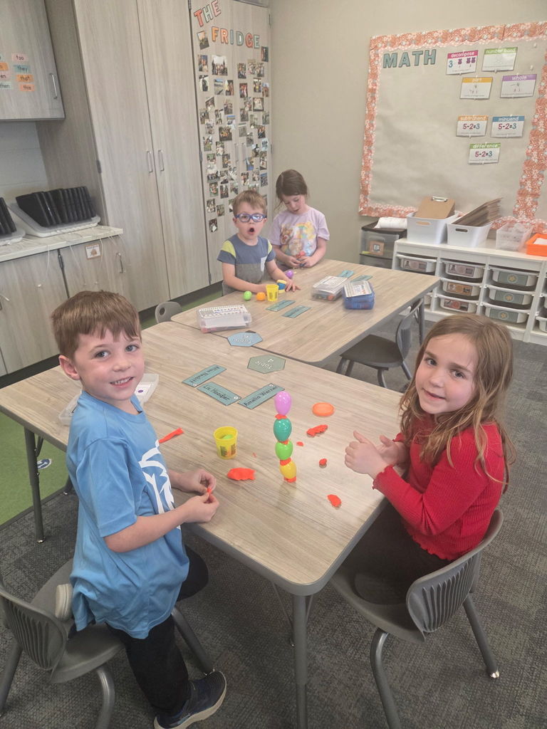 students playing with playdoh and stacking eggs in a classroom for a stem activity.
