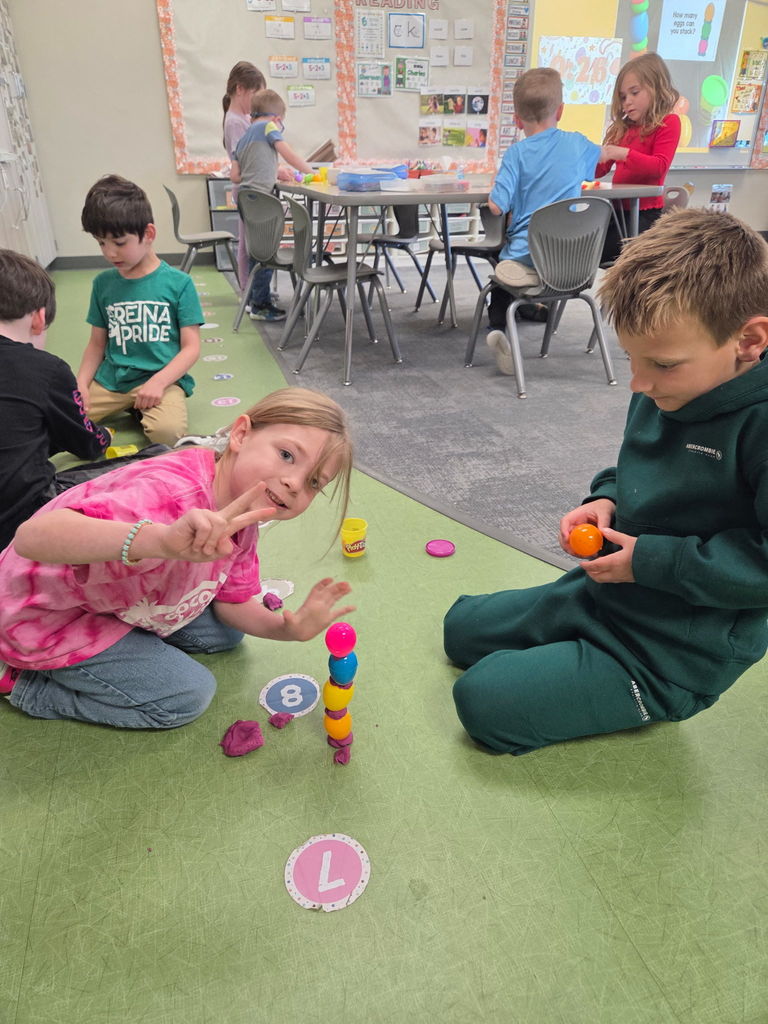 students playing with playdoh and stacking eggs in a classroom for a stem activity.